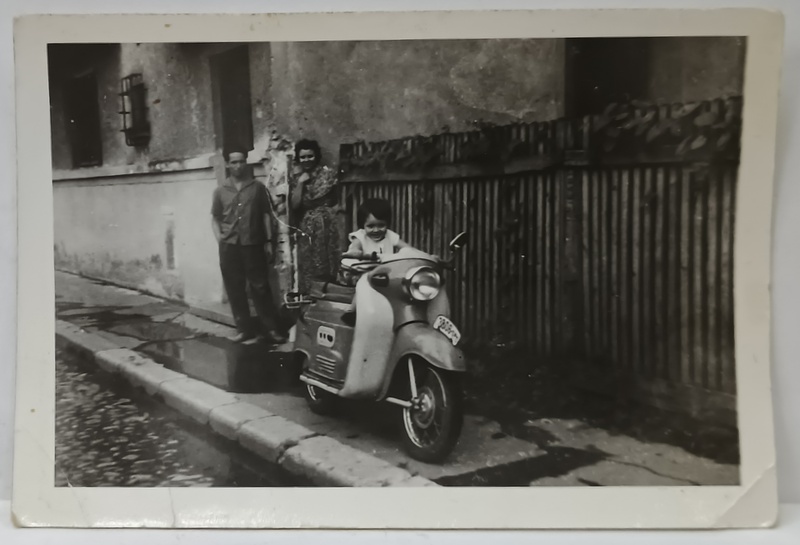 COPIL PE MOTORETA ' MANET ' IN FATA CASEI , CU PARINTII , FOTOGRAFIE DE MICI DIMENSIUNI , ANII ' 60